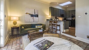 Un salon comprenant un canapé, une table basse et un coin repas avec une table et des chaises. Il y a également une cuisine équipée avec des placards et des appareils électroménagers.
