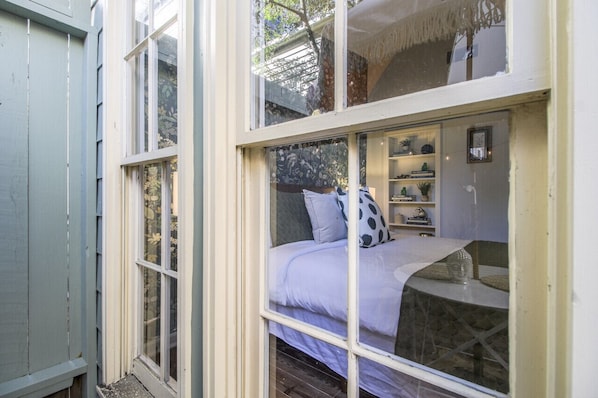 A room with a bed, a window, and shelves with items.