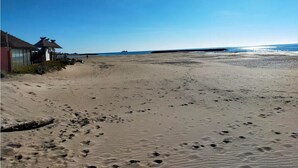 A sandy beach with footprints, a building with a red roof, and a clear blue sky. - Mobil-home au Camping 4 Étoiles Familial Les Sables D'or (Agde)