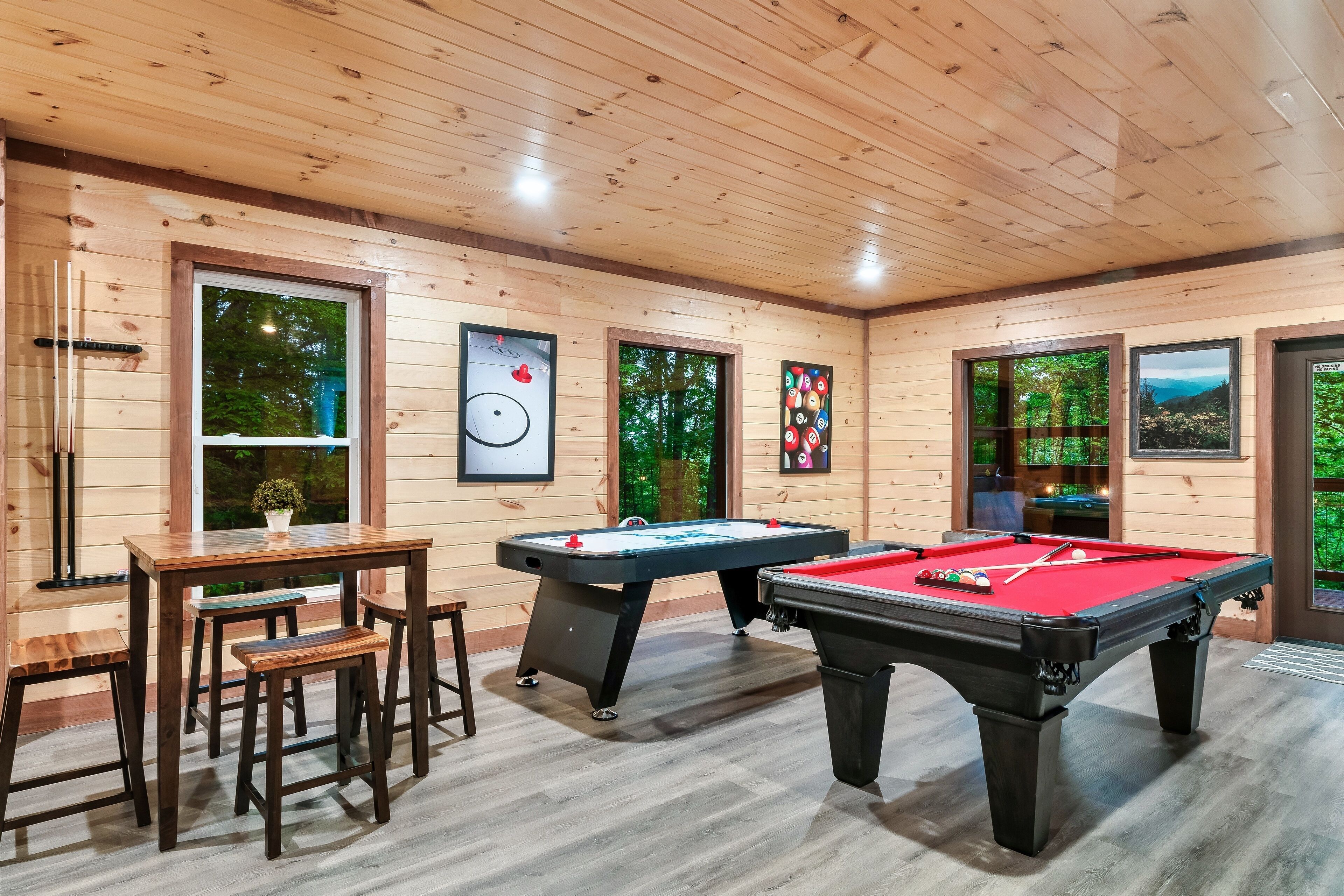 Een houten ruimte met twee pooltafels, een biljarttafel en een klein zitgedeelte.
