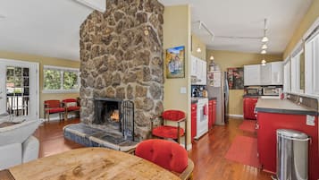 Una cocina moderna con chimenea de piedra, taburetes rojos y una mesa de comedor de madera.