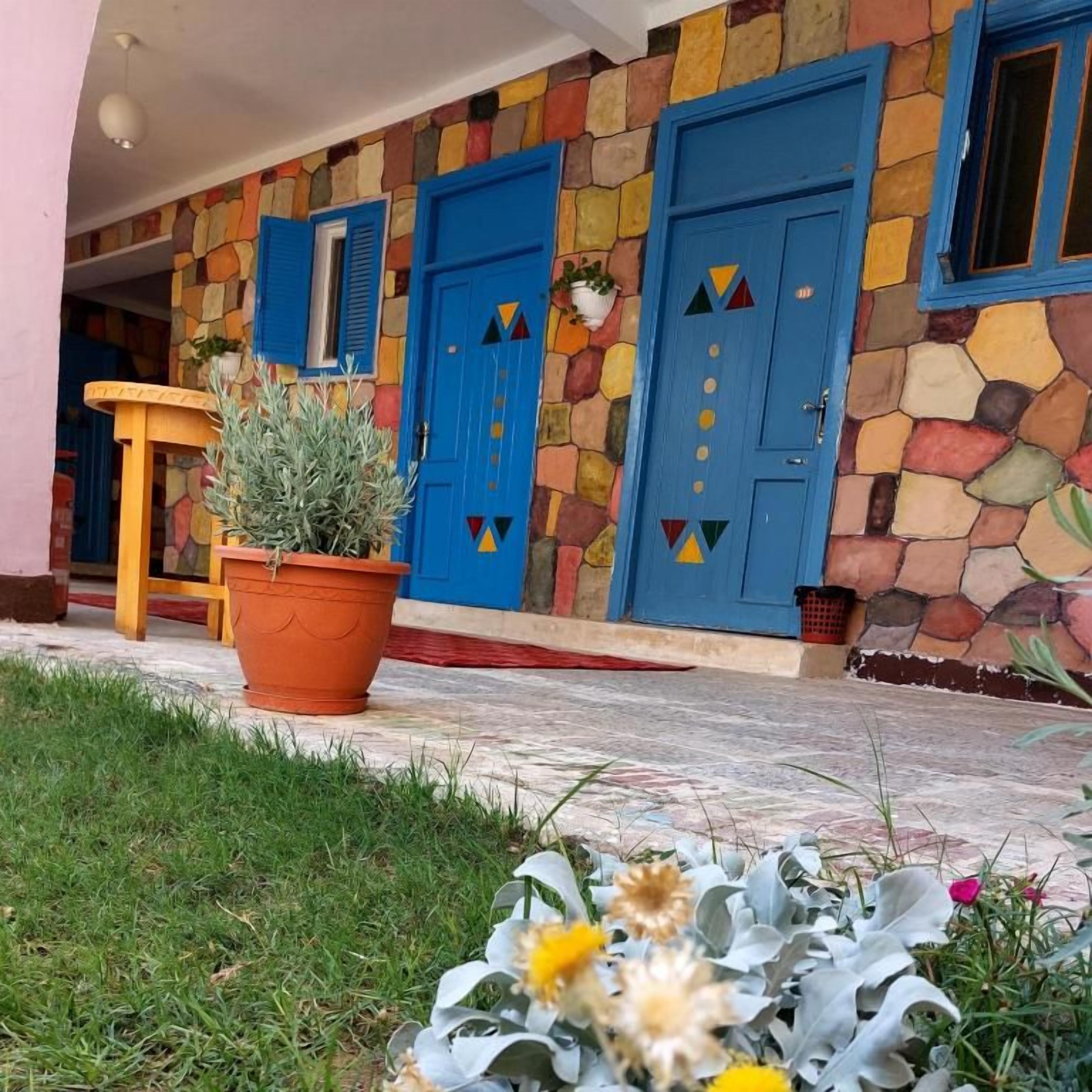 Ein Gebäude mit einer steinernen Fassade, blauen Türen und einem Blumentopf im Vordergrund.