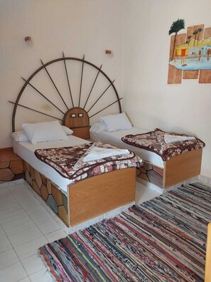 A bedroom with two beds, a unique fan-shaped headboard, a patterned rug, and a small wall art piece. - Hllol Hotel Abu Simbel (Abu Simbel)