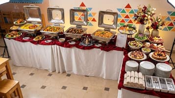 A buffet setup with various food items and a floral centerpiece.