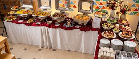 Un buffet allestito con diversi cibi e un composizione floreale al centro.
