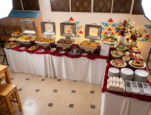 Montaje de bufé con diferentes alimentos y un centro de mesa floral.