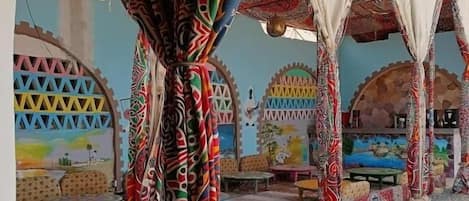 A room with patterned curtains, a tiled floor, and a view of the outside.