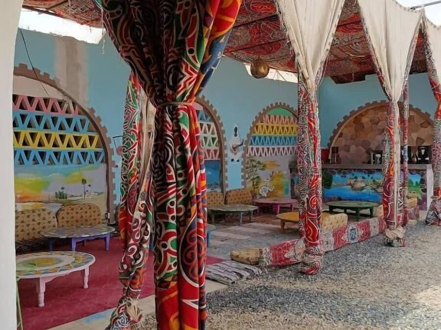 A room with patterned curtains, a tiled floor, and a view of the outside.
