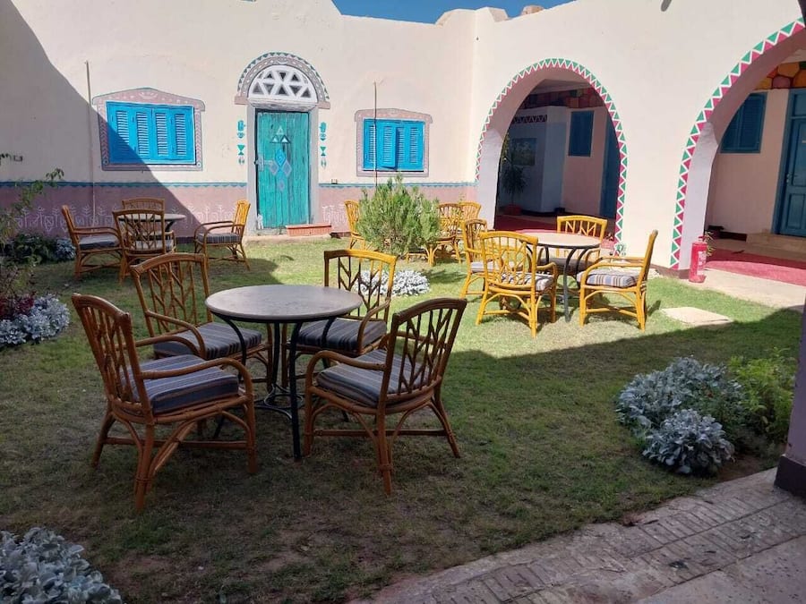 A courtyard with outdoor seating and a building with blue doors and shutters.