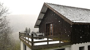 Une cabane en bois dotée d’un balcon, d’un garage et offrant une vue sur le paysage environnant.