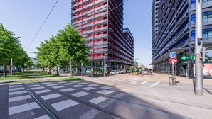 Eine moderne Stadtstraße mit Straßenbahnschienen, hohen Gebäuden und einer Fußgängerüberquerung.