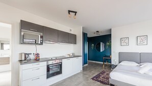 Eine moderne Küche mit Mikrowelle, Backofen und Spüle, ein Schlafzimmer mit Bett und Nachttisch, und eine blaue Akzentwand.