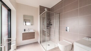 Ein modernes Badezimmer mit einer Duschkabine, einer Toilette und einem Waschbecken mit Spiegel darüber.