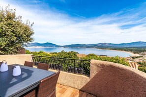Zona pranzo all'aperto con tavolo e sedie, affacciata su un panorama suggestivo di un lago e delle montagne.