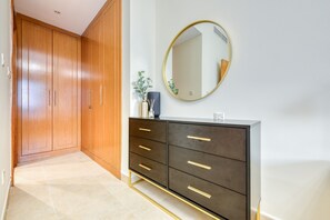 Stylish room with a large wardrobe, dresser, and round mirror, featuring a touch of greenery.
