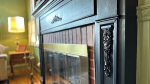 Une cheminée agrémentée d’un manteau décoratif et d’un radiateur en laiton.