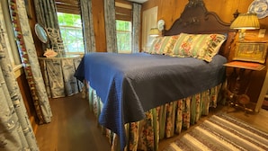 A bedroom with a large bed, floral curtains, a wooden headboard, and a striped rug.
