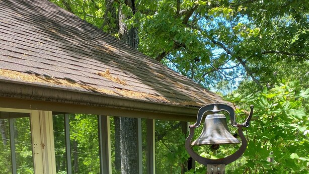 A rustic building with a porch, a bell, and a statue.