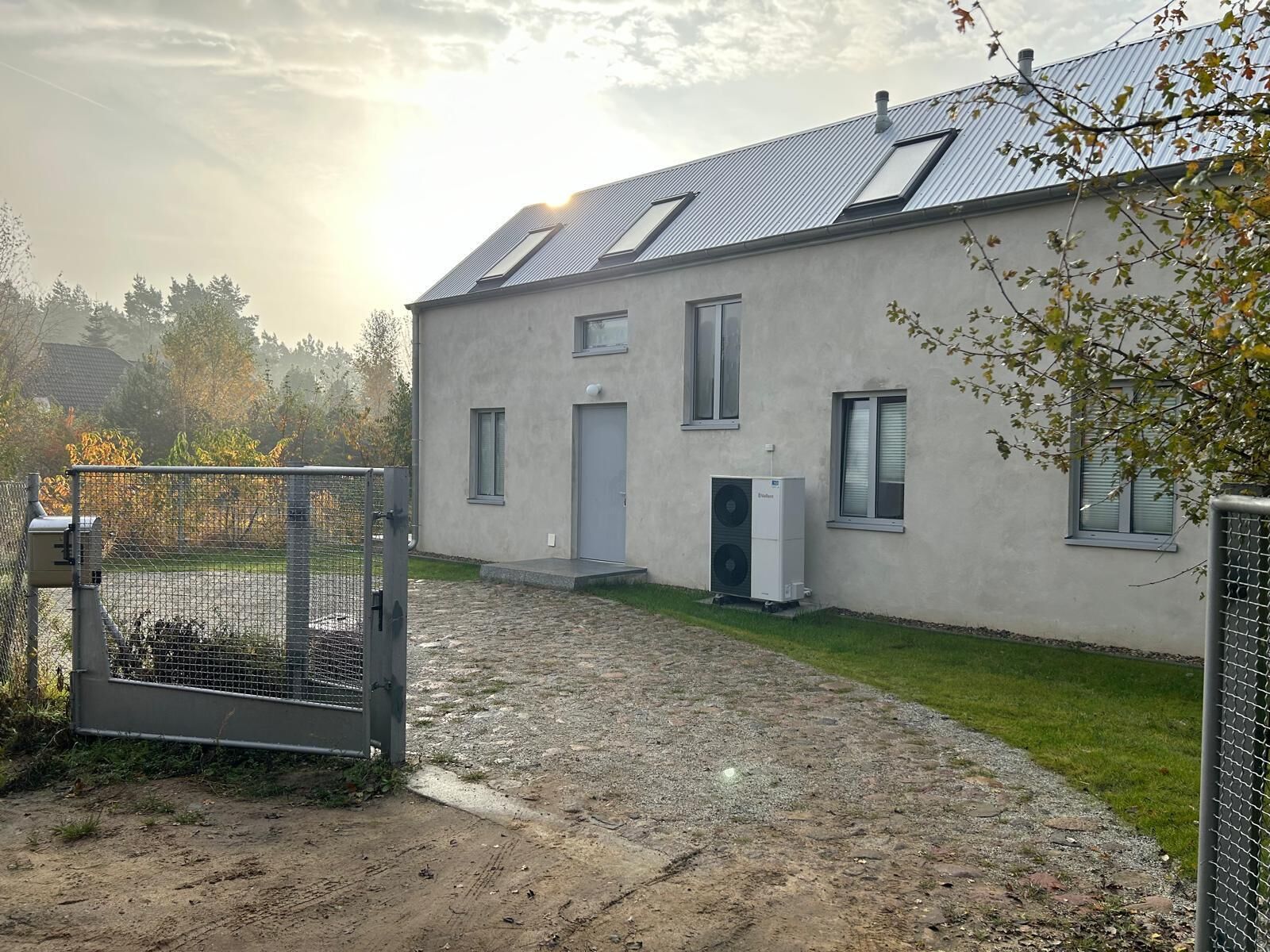 Ein Haus mit befestigter Auffahrt, einem Metallzaun und einer Solaranlage auf dem Dach.