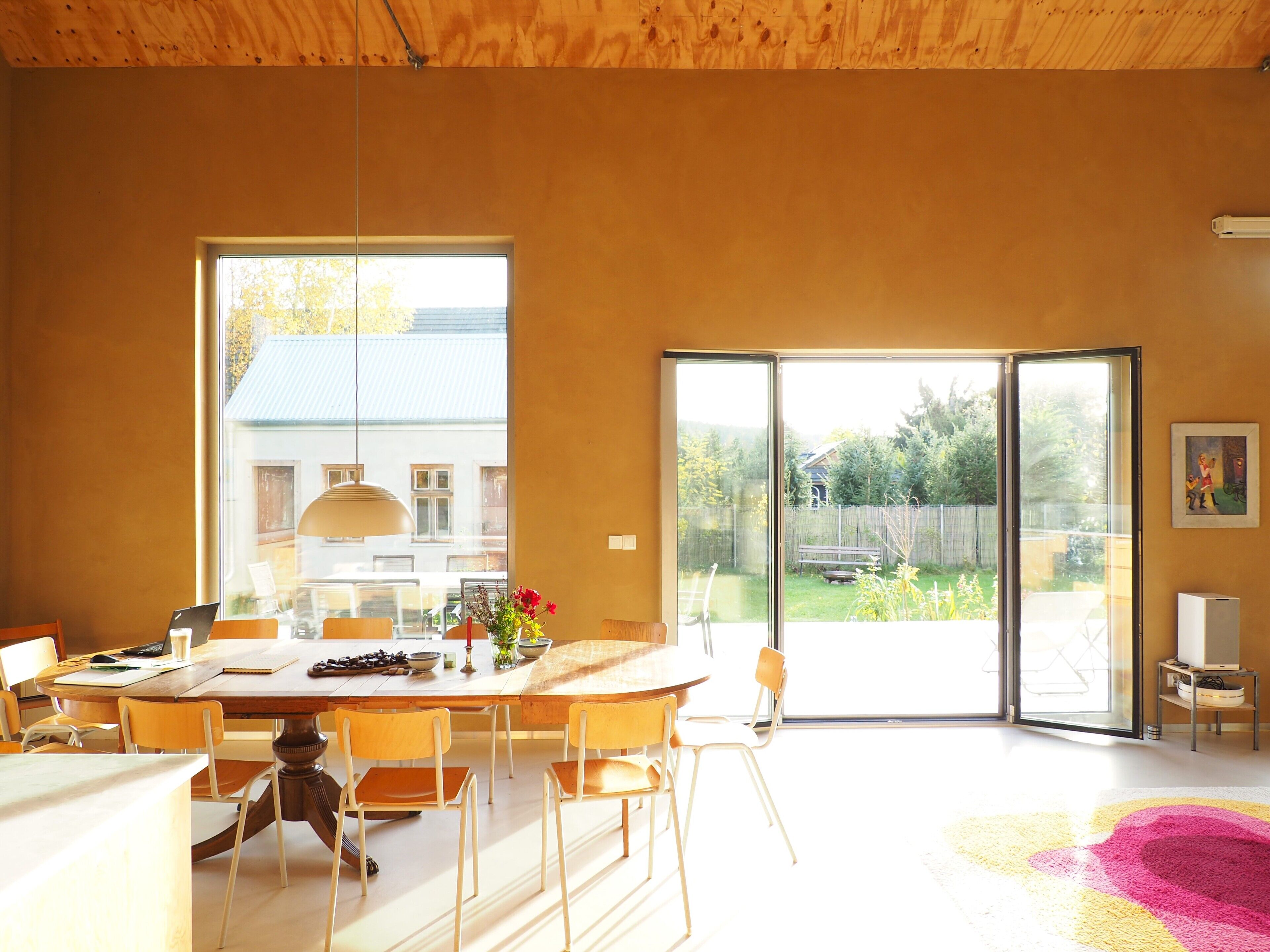 Un comedor moderno con una mesa grande, sillas y vistas al exterior a través de un ventanal corredero.
