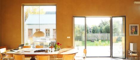 Un comedor moderno con una mesa grande, sillas y vistas al exterior a través de un ventanal corredero.