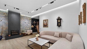A modern living room with a fireplace, a sofa, a coffee table, and a bookshelf.