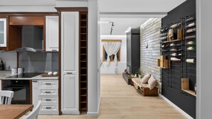 A modern kitchen with white cabinetry, a built-in oven, and a dining area with a wooden table and chairs.