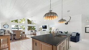 Una cocina moderna con una isla central, armarios de madera e iluminación colgante.