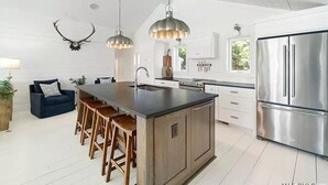 Una cocina moderna con una isla central, electrodomésticos de acero inoxidable e iluminación colgante.