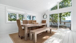 Un comedor con una mesa de madera, sillas de mimbre y un banco.