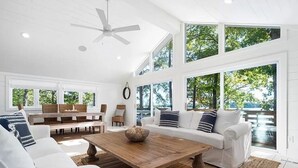 Un salón amplio con una gran mesa de centro de madera, sofás blancos y una zona de comedor con mesa y sillas de madera.
