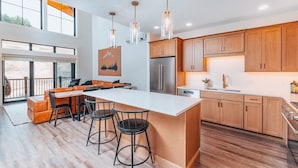 A modern kitchen with a large island, wooden cabinets, and pendant lighting. - Slopeside Luxe-Upgrade Adventure (Conway)