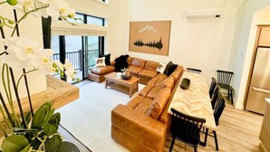 A spacious living area with a large sofa set, a dining table, and a kitchen area. - Slopeside Luxe-Upgrade Adventure (Conway)
