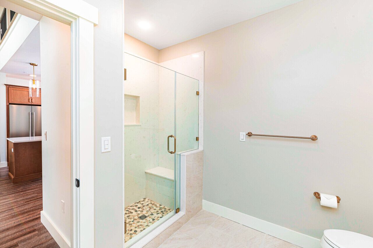 A modern bathroom with a glass shower enclosure, a toilet, and a towel rack.