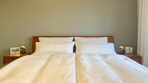 Cama bem arrumada com lençóis brancos em quarto de hotel com cabeceira de madeira.