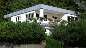 Uma casa moderna de dois andares com telhado plano, janelas amplas e base de pedra.