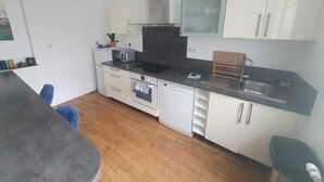 A compact kitchen with white cabinets, a black countertop, and a stainless steel sink. - Appartement T3 Refait à Neuf Calme et Centrale, Parking Privé, 5min de la Gare (Tours)