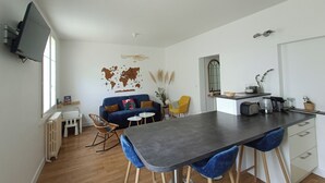 A modern kitchen with a dining area, a blue sofa, and a world map on the wall. - Appartement T3 Refait à Neuf Calme et Centrale, Parking Privé, 5min de la Gare (Tours)
