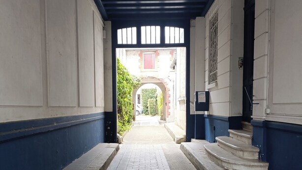 A narrow brick pathway leading to a building entrance with a blue and white facade. - Appartement T3 Refait à Neuf Calme et Centrale, Parking Privé, 5min de la Gare (Tours)