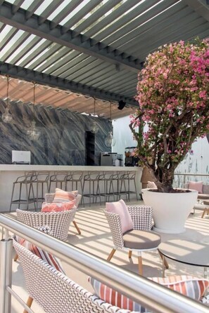 An outdoor seating area with wicker chairs and a large potted tree. - Xhiara Hotel (Xochitepec)