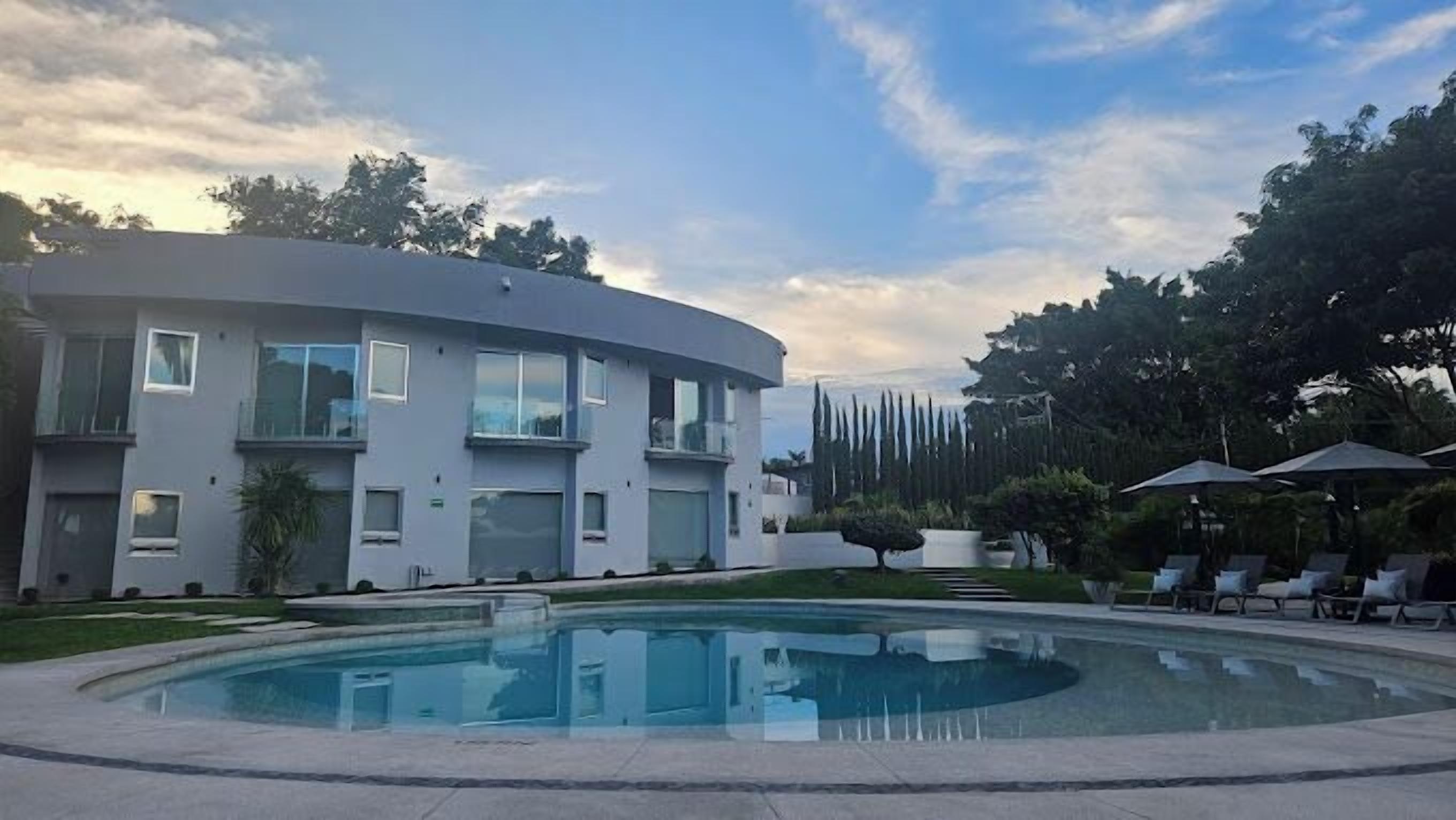 A modern two-story building with a pool and outdoor seating.