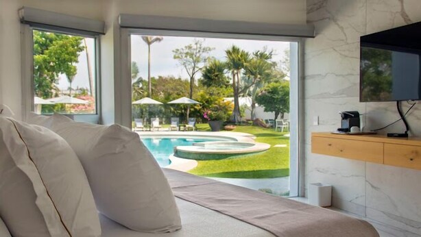 Un dormitorio con cama, televisor y vistas a una piscina y jardín.