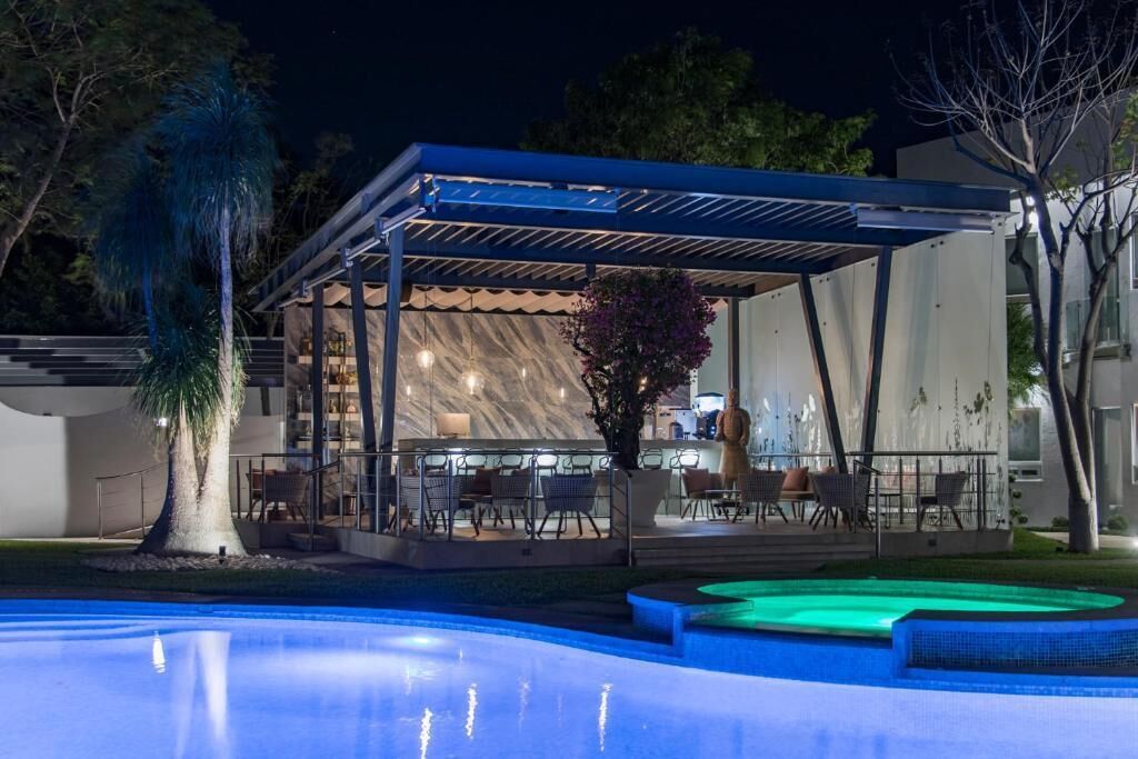 Un área junto a la piscina con una zona de estar techada, piscina y un edificio de diseño moderno.