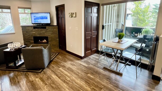 A modern living room with a fireplace, a flat-screen TV, and a dining area with a glass table and chairs.