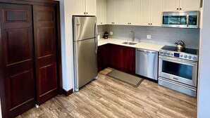A modern kitchen with stainless steel appliances, wooden cabinets, and a tiled backsplash.