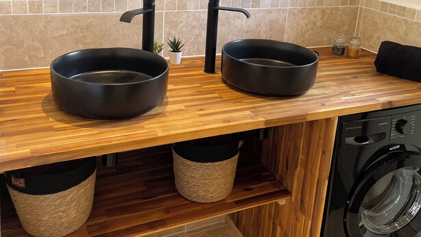 A modern bathroom with two round mirrors, a wooden vanity, a washing machine, and a small potted plant. - Gîte la Chotinière (Mareuil-sur-Cher)