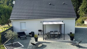 A white building with a dark roof, outdoor seating area, and a gravel patio. - Gîte la Chotinière (Mareuil-sur-Cher)
