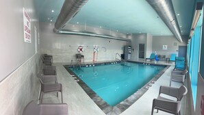 A swimming pool with lifebuoys, lounge chairs, and a pool lift sign. - avid Hotel Harrisburg NE Hershey Area by IHG (Harrisburg)