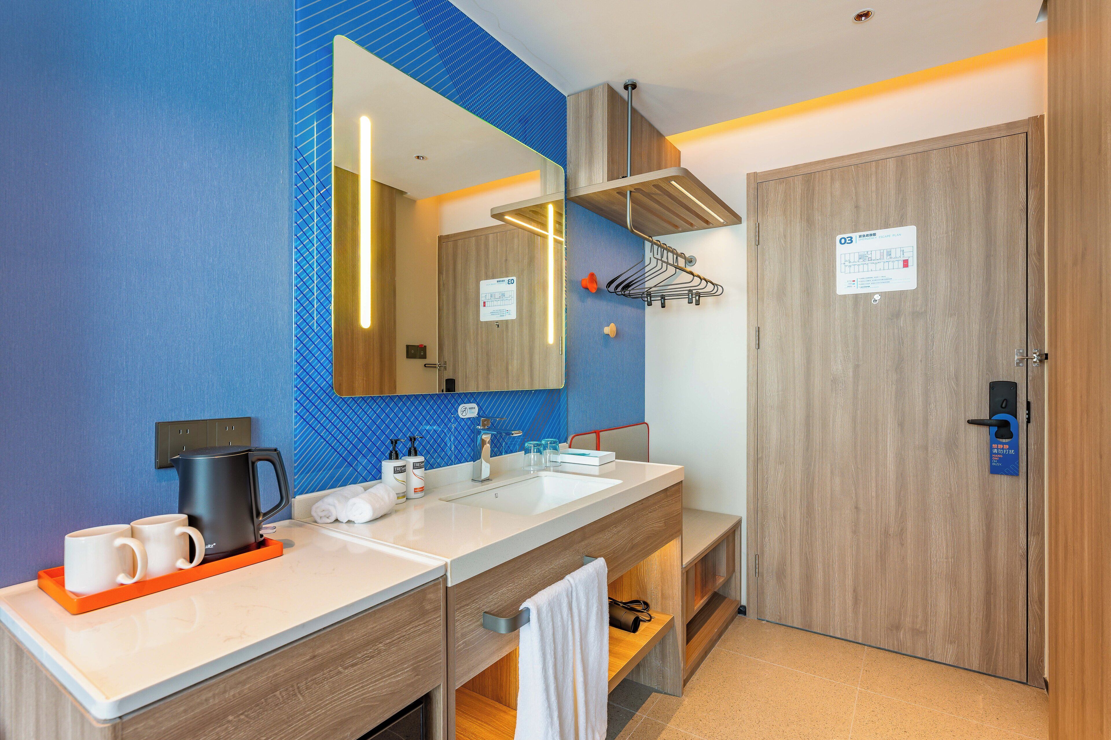 A modern bathroom with a large mirror, two sinks, a towel rack, and a shower area.