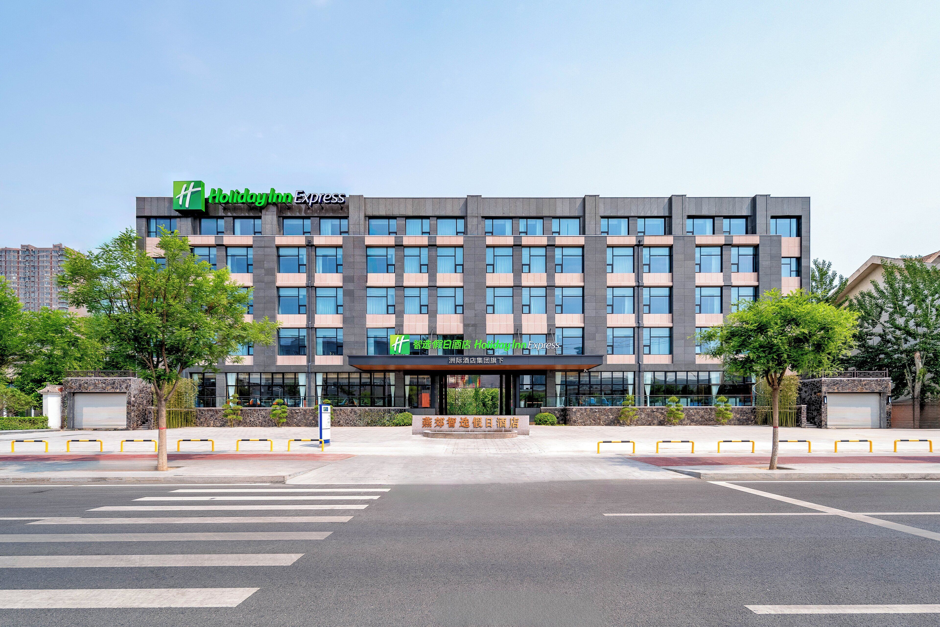 Un hotel Holiday Inn Express con fachada moderna, ventanas grandes y una entrada central.